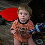 Jameson joined the competition — help win amazing prizes! toddler, child, indoor, floor, toy, basket, orange_shirt, curious, sitting, wooden_floor, diaper, expressionless, holding_object, playtime, home, casual_clothing, short_hair, young_child, person, blue_toy