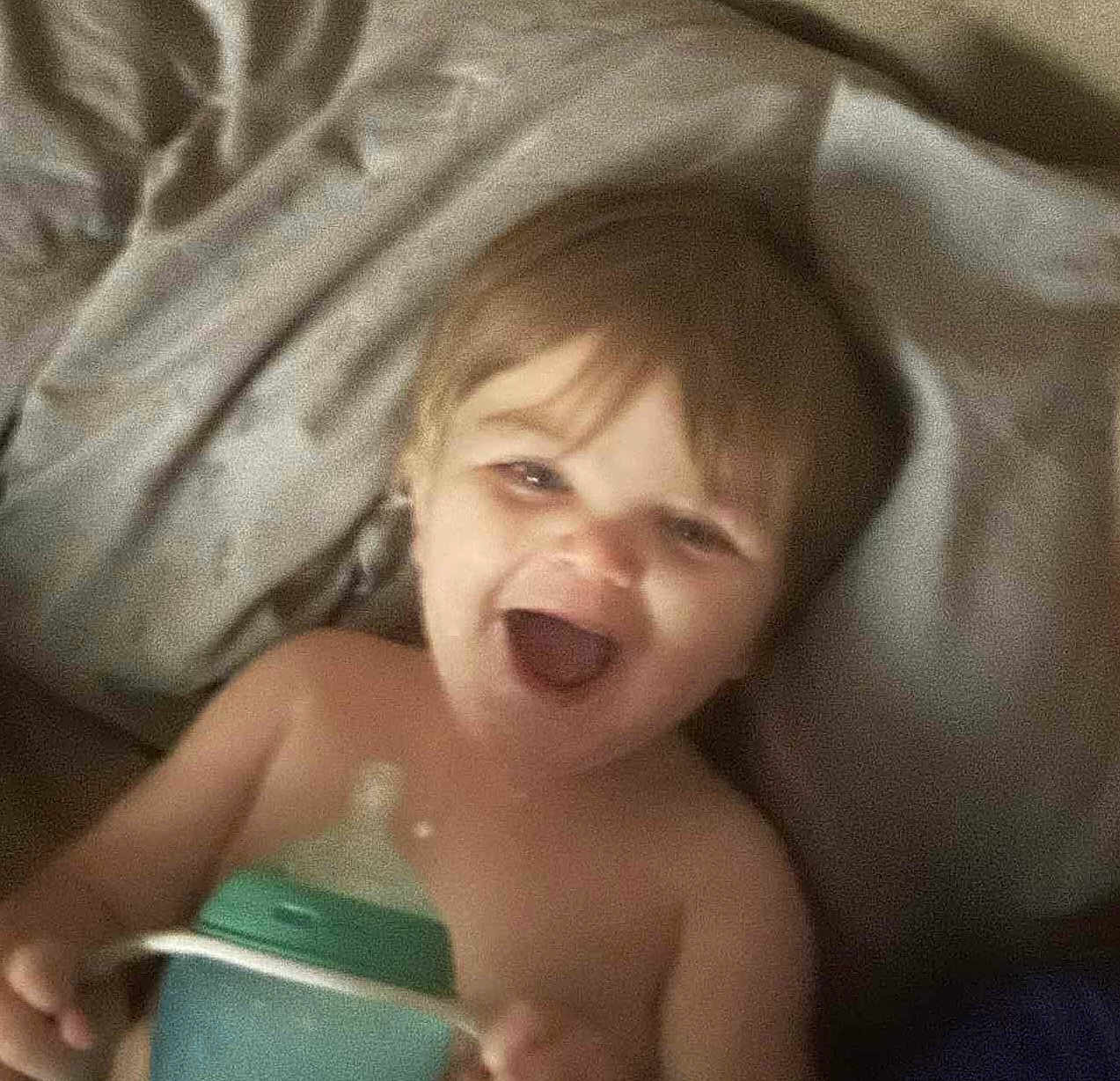 Jameson is registered to the contest to win money with this photo: toddler, baby, smiling, laughing, bottle, child, indoor, blanket, happy, young, cute, face, skin, hair, hand, lying_down, comfort, infant, expression, playful