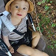 Noah William Bastos a rejoint le concours — aidez-le/la à gagner de superbes lots ! toddler, child, hat, stroller, outdoor, leaves, tree_bark, striped_shirt, shorts, footwear, happy, curious, baby, nature, seat_belt, playful, summer, smiling, person, portrait