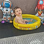 astronaut, balloons, child, cute, floor, fun, happy, inflatable_pool, outdoor, plastic, play, rocket, sitting, smiling, toddler, toy, wall, water, water_play, yellow