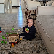 Isra a rejoint le concours — aidez-le/la à gagner de superbes lots ! building_blocks, casual_clothing, chairs, child, container, curly_hair, daylight, floor, glass, home, indoor, living_room, person, playing, rug, sofa, table, toddler, topknot, toys