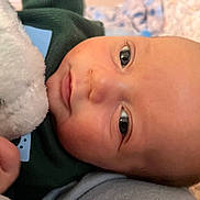 Parker is registered to the contest to win money with this photo: baby, closeup, face, infant, soft_toy, blanket, hand, skin, eyes, expression, cute, child, portrait, warm, cozy, indoor, newborn, comfort, clothing, sleepwear