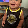 toddler, child, smiling, sitting, couch, indoors, clothing, basketball, television, cartoon, person, happy, face, furniture, room, casual, cute, portrait, black_clothing, yellow_trim