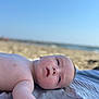 baby, beach, child, closeup, cute, daylight, face, infant, lying_down, outdoor, peaceful, portrait, relaxing, sand, skin, sky, summer, sunlight, towel, vacation