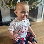 Kyren joined the competition — help win amazing prizes! baby, child, christmas_tree, cute, decorations, festive, floor, happy, holiday, holiday_clothing, holiday_season, indoors, infant, plaid_pants, portrait, sitting, smiling, white_shirt, wooden_floor, young_child