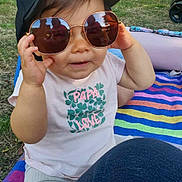 Jade a rejoint le concours — aidez-le/la à gagner de superbes lots ! baseball_cap, blanket, casual_clothing, child, grass, hand, happy, leg, nature, outdoor, pants, park, person, playing, reflection, shirt, summer, sunglasses, sunlight, toddler