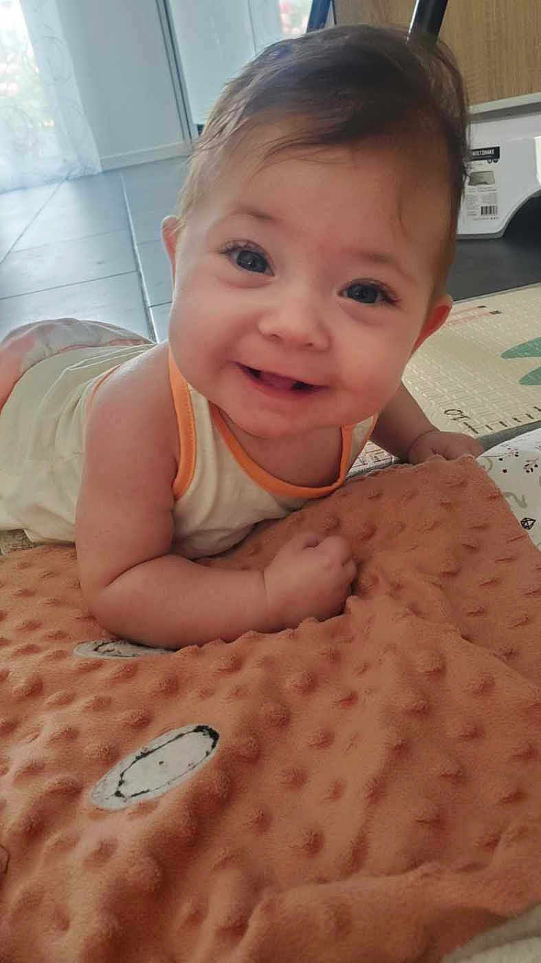 Alba a rejoint le concours — aidez-le/la à gagner de superbes lots ! baby, smiling, face, infant, blanket, happy, cute, indoors, child, toddler, skin, head, eyes, mouth, person, hands, clothing, floor, expression, portrait
