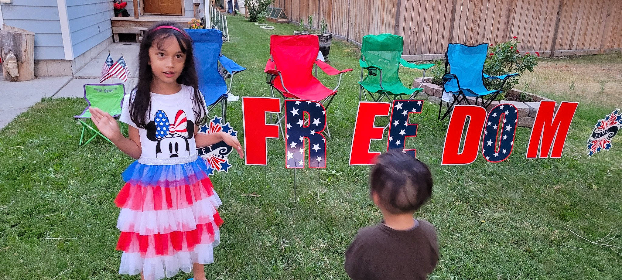 Isabelle is registered to the contest to win money with this photo: chair, clothing, event, flag_of_the_united_states, fun, grass, green, hat, holiday, lawn, leisure, party_supply, person, plant, recreation, shoe, t_shirt, textile, toddler, tree