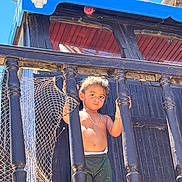 Naim Fridhi a rejoint le concours — aidez-le/la à gagner de superbes lots ! child, toddler, boy, shirtless, shorts, bracelet, necklace, wooden_railings, netting, pirate_ship, skull_decoration, blue_sky, outdoor, sunlight, daytime, portrait, serious_expression, standing, playground, adventure