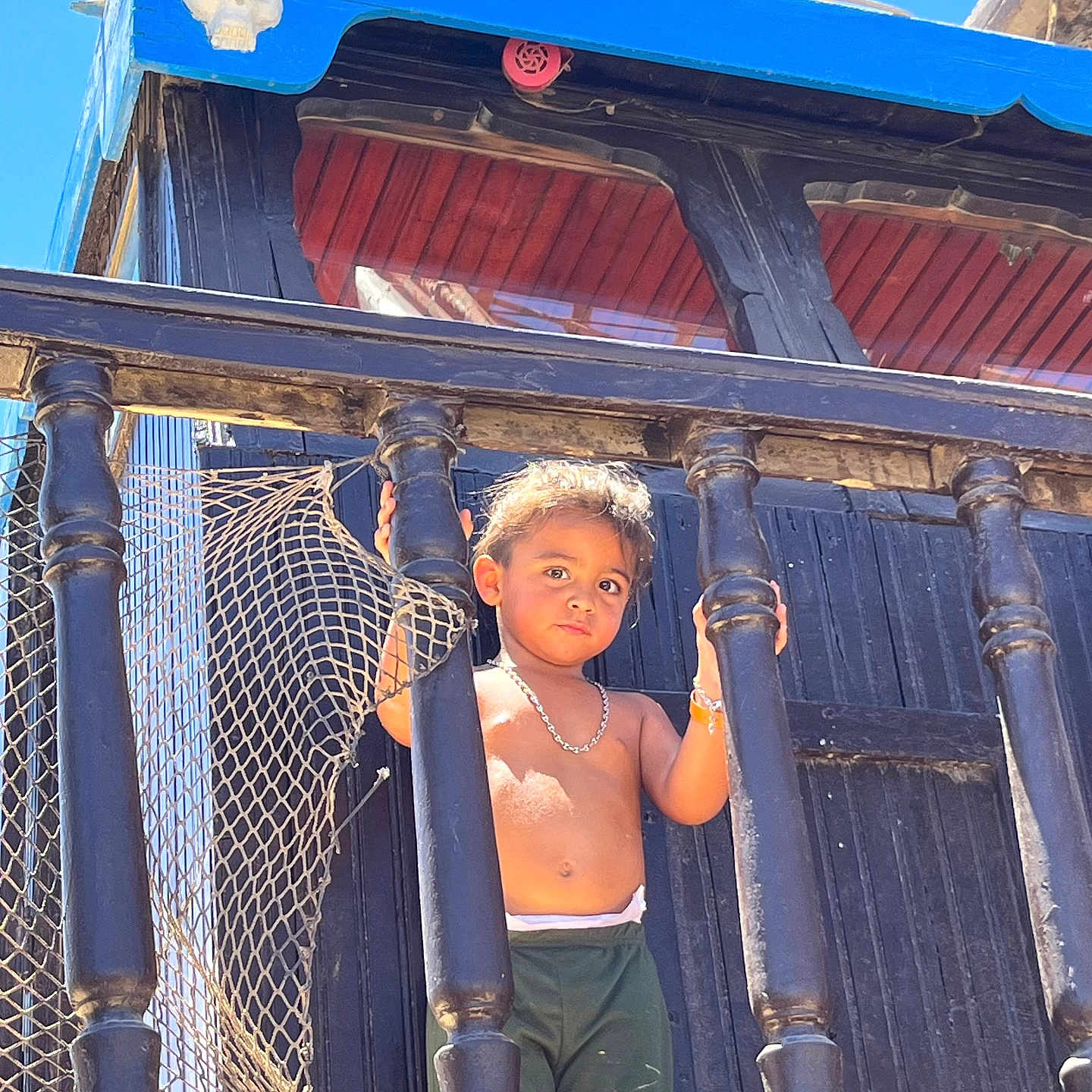 Naim Fridhi a rejoint le concours — aidez-le/la à gagner de superbes lots ! adventure, blue_sky, boy, bracelet, child, daytime, necklace, netting, outdoor, pirate_ship, playground, portrait, serious_expression, shirtless, shorts, skull_decoration, standing, sunlight, toddler, wooden_railings