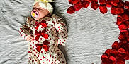 Evie is registered to the contest to win money with this photo: adorable, baby, bed, bow, cute, headband, heart_pattern, heart_shape, infant, love, lying_down, newborn, onesie, pacifier, red_bows, rose_petals, sleeping, soft_lighting, toddler, white_sheet