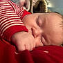 baby, sleeping, infant, closeup, face, hand, red_clothing, striped_sleeve, skin, peaceful, rest, cozy, soft_light, indoors, newborn, portrait, cute, child, nap, comfort