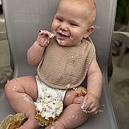Jaxon is registered to the contest to win money with this photo: baby, child, cupcake, frosting, sprinkles, messy, smiling, sitting, bib, diaper, happy, food, chair, indoor, cute, chubby, hands, legs, face, celebration