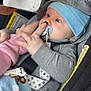 baby, blanket, blue_hat, car, car_seat, child, closeup, cute, grey_clothing, hand, holding, indoor, infant, pacifier, person, portrait, seatbelt, smartphone, technology, young_child