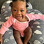 baby, child, smiling, pink_clothing, curly_hair, cushion, gray, cloud_pattern, rainbow_pattern, indoors, happy, person, cute, infant, sitting, portrait, skin, hand, foot, cozy
