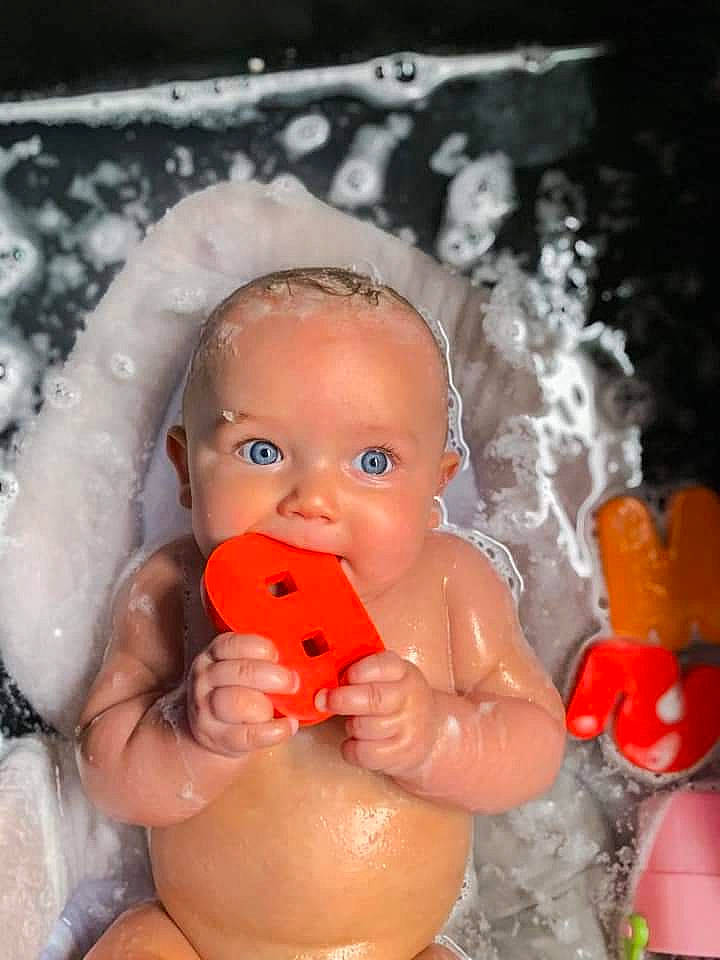 Everly is registered to the contest to win money with this photo: arm, baby, bathing, cheek, chest, eye, eyebrow, finger, hand, happy, head, human_body, iris, lip, mouth, muscle, nose, orange, person, skin