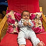 Adam a rejoint le concours — aidez-le/la à gagner de superbes lots ! baby, child, smile, red_chair, wooden_chair, pillow, floral_pillow, toy, happy, indoors, foot, clothing, long_sleeve, pants, person, face, comfort, seated, cute, home