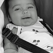 Alani-May is registered to the contest to win money with this photo: baby, smiling, infant, face, car_seat, safety_strap, clothing, pattern, black_and_white, cute, child, hand, closeup, portrait, happy, seatbelt, head, eyes, skin, babywearing
