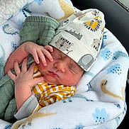 Onyx joined the competition — help win amazing prizes! newborn, baby, sleeping, blanket, hat, infant, clothing, cute, hand, face, car_interior, pattern, soft_texture, cozy, child, resting, wrapped, animal_print, peaceful, indoors