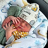 newborn, baby, sleeping, blanket, hat, infant, clothing, cute, hand, face, car_interior, pattern, soft_texture, cozy, child, resting, wrapped, animal_print, peaceful, indoors