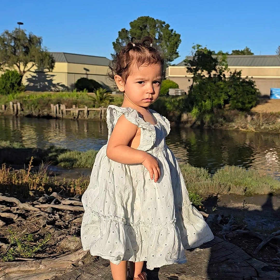 Mia joined the competition — help win amazing prizes! child, clothing, dress, face, female, girl, head, nature, outdoors, person, photography, plant, pond, portrait, rock, sitting, tree, water, waterfront, wood