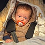 Ezio participe au concours pour gagner de l'argent avec cette photo : baby, pacifier, blanket, car_seat, stroller, warm_clothing, hoodie, blue_eyes, face, infant, child, person, hand, comfort, sleepy, indoors, soft_texture, patterned_fabric, closeup, portrait