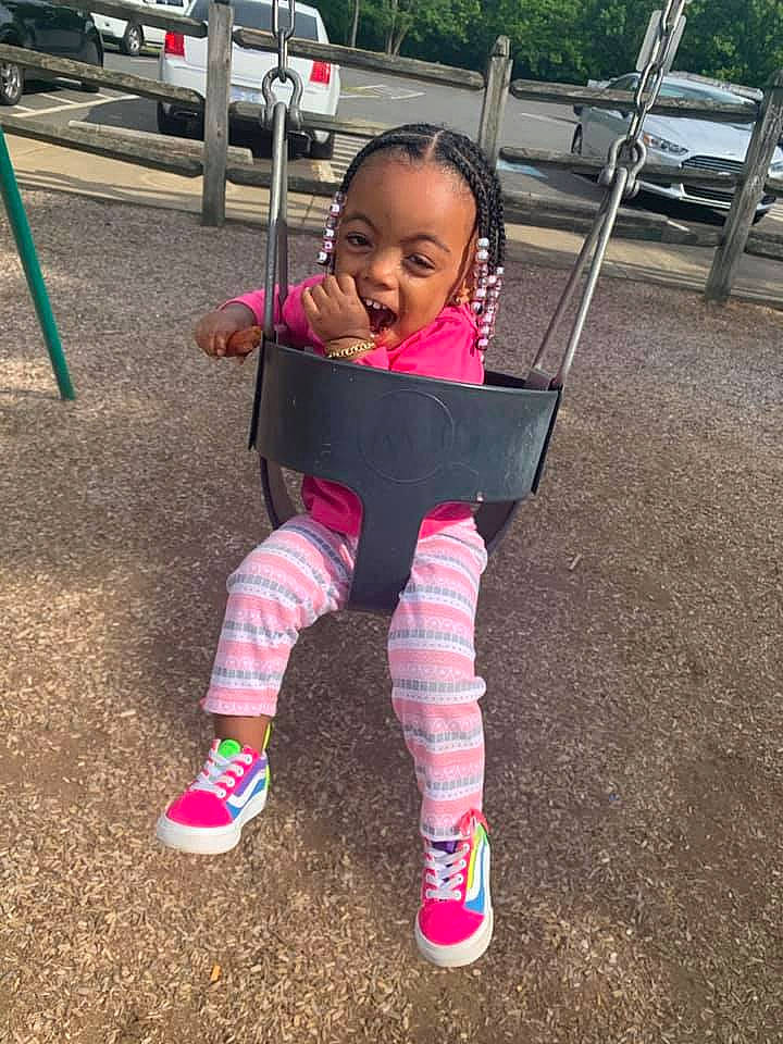 Takhari is registered to the contest to win money with this photo: baby, baby_toddler_clothing, car, city, face, grass, happy, leisure, magenta, outdoor_play_equipment, person, plant, recreation, sleeve, smile, sneakers, sock, swing, toddler, tree