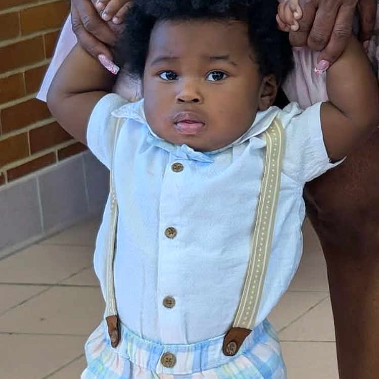 Keion Thomas joined the competition — help win amazing prizes! adult_hands, baby, brick_wall, buttoned_shirt, child, curious, curly_hair, cute, fashion, holding_hands, indoor, legs, person, plaid_shorts, portrait, serious, standing, suspenders, tiled_floor, toddler