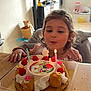 child, birthday_cake, candle, cream, raspberries, table, living_room, window, television, furniture, celebration, person, smiling, happy, indoor, party, dessert, food, decorations, cake_topper
