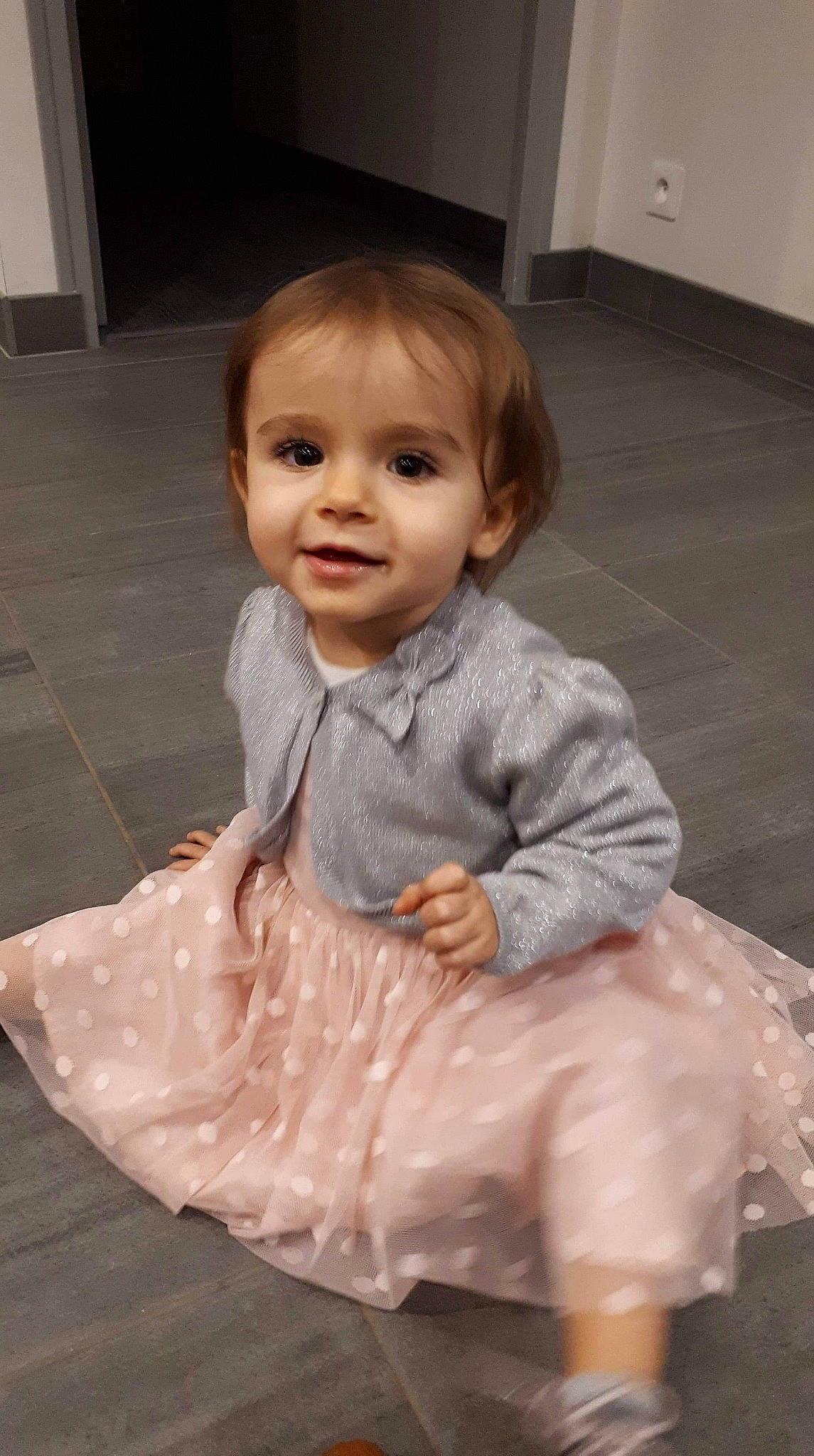 Lüna participe au concours pour gagner de l'argent avec cette photo : child, dress, floor, flooring, fun, girl, hair, head, human_hair_color, infant, outerwear, person, sitting, skin, smile, standing, textile, toddler