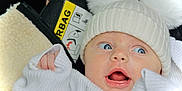 Anastasia joined the competition — help win amazing prizes! baby, infant, face, blue_eyes, hat, pom_poms, knitwear, white_clothing, hand, car_seat, airbag_warning, expression, surprised, curious, closeup, portrait, child, cute, cozy, warm