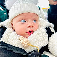 Anastasia is registered to the contest to win money with this photo: baby, infant, blue_eyes, white_hat, pom_poms, sherpa_jacket, pacifier, close_up, outdoor, winter_clothing, cute, child, portrait, soft_texture, warm_clothing, curious, face, person, headwear, expression