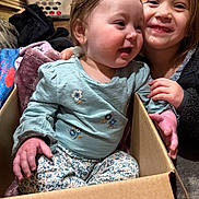 Maliah is registered to the contest to win money with this photo: child, baby, cardboard_box, smiling, cute, indoor, family, sitting, clothing, blanket, happy, young_sibling, baby_girl, toddler, home, laundry_basket, casual, playful, portrait, face