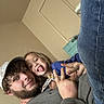 child, man, indoor, casual_clothing, playful, smiling, tongue_out, hat, beard, jeans, sweater, door, hand_gesture, family, candid, happy, person, home, light_skin, curly_hair