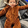 Paisley Rae is registered to the contest to win money with this photo: baby, blanket, brown_clothing, child, cozy, cute, eyes, face, fur_clothing, hood, indoor, infant, lying_down, onesie, person, portrait, smile, soft, texture, warm_clothing