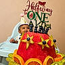 baby, child, half_birthday, party_hat, high_chair, watermelon, fruit_cake, blueberries, starfruit, orange_slices, kiwi, celebration, smiling, food, plate, indoor, person, happy, birthday, decorations