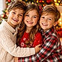 child, children, smiling, group_hug, christmas_tree, holiday_lights, sweater, red_sweater, plaid_shirt, winter_clothing, indoor, happy, family, festive, decorations, blond_hair, long_hair, casual, friendship, portrait