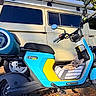 dog, french_bulldog, puppy, pet, animal, scooter, segway, basket, vehicle, motorized_vehicle, van, outdoor, sunlight, street, parked, blue, yellow, transportation, portrait, ears