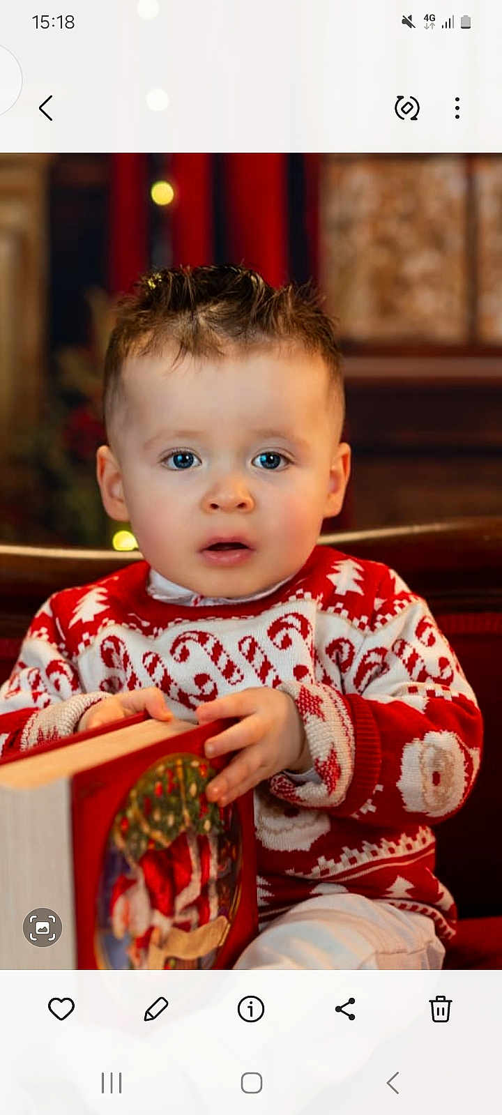 Romeo James is registered to the contest to win money with this photo: blue_eyes, book, child, christmas, cozy, curly_hair, cute, face, festive, hands, holiday, indoors, portrait, red, seated, sweater, toddler, white, winter, young
