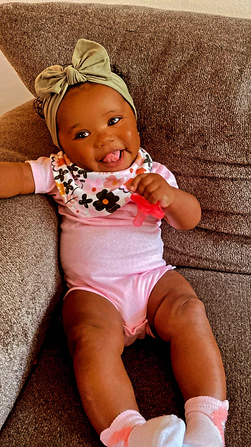 Sophia is registered to the contest to win money with this photo: baby, baby_toddler_clothing, eye, face, facial_expression, hand, head, human_body, joint, knee, mouth, muscle, orange, person, pink, shorts, skin, smile, stomach, thigh