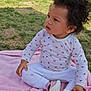 toddler, child, curly_hair, pink_blanket, outdoor, grass, white_clothing, butterfly_print, pink_shoes, sitting, cross_legged, cute, young_child, casual_wear, daylight, person, baby, small_shoes, nature, curious