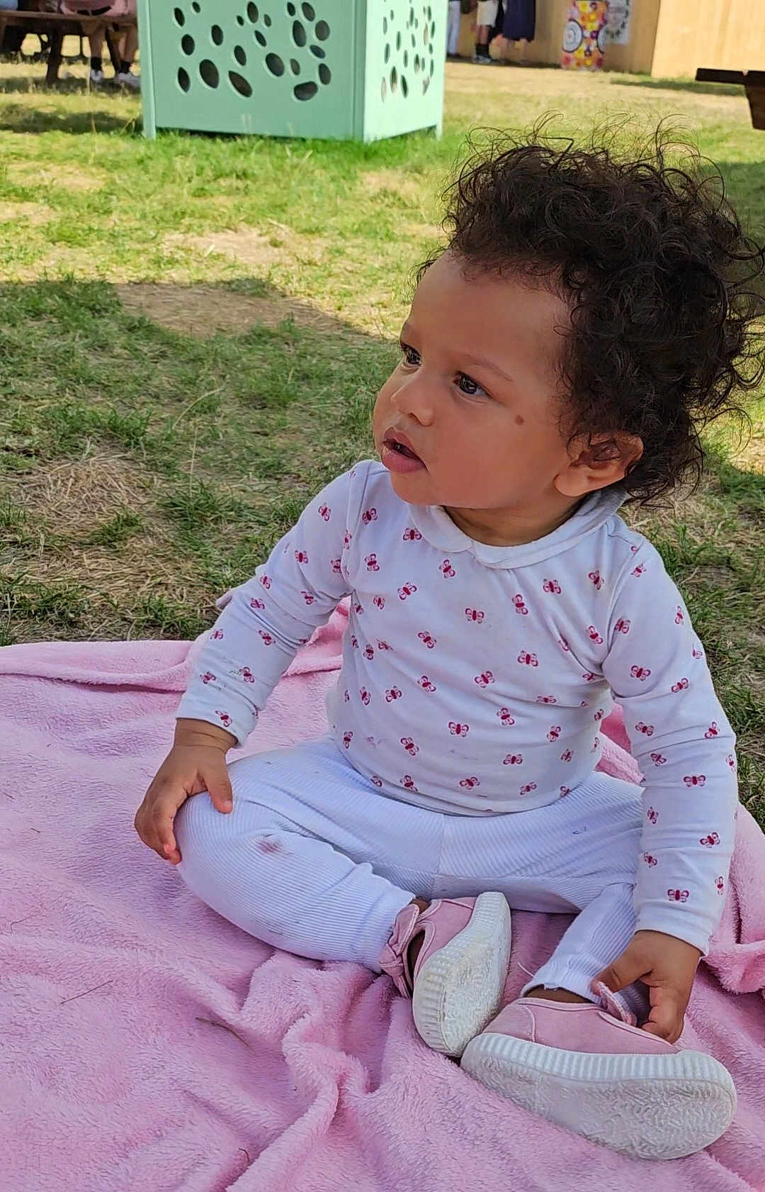 Kalysia participe au concours pour gagner de l'argent avec cette photo : toddler, child, curly_hair, pink_blanket, outdoor, grass, white_clothing, butterfly_print, pink_shoes, sitting, cross_legged, cute, young_child, casual_wear, daylight, person, baby, small_shoes, nature, curious