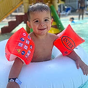Jules participe au concours pour gagner de l'argent avec cette photo : child, toddler, pool, water, floaties, inflatable_ring, swimming, summer, wet_hair, smiling, outdoor, playground, slide, water_play, fun, happy, vacation, sunlight, recreation, leisure