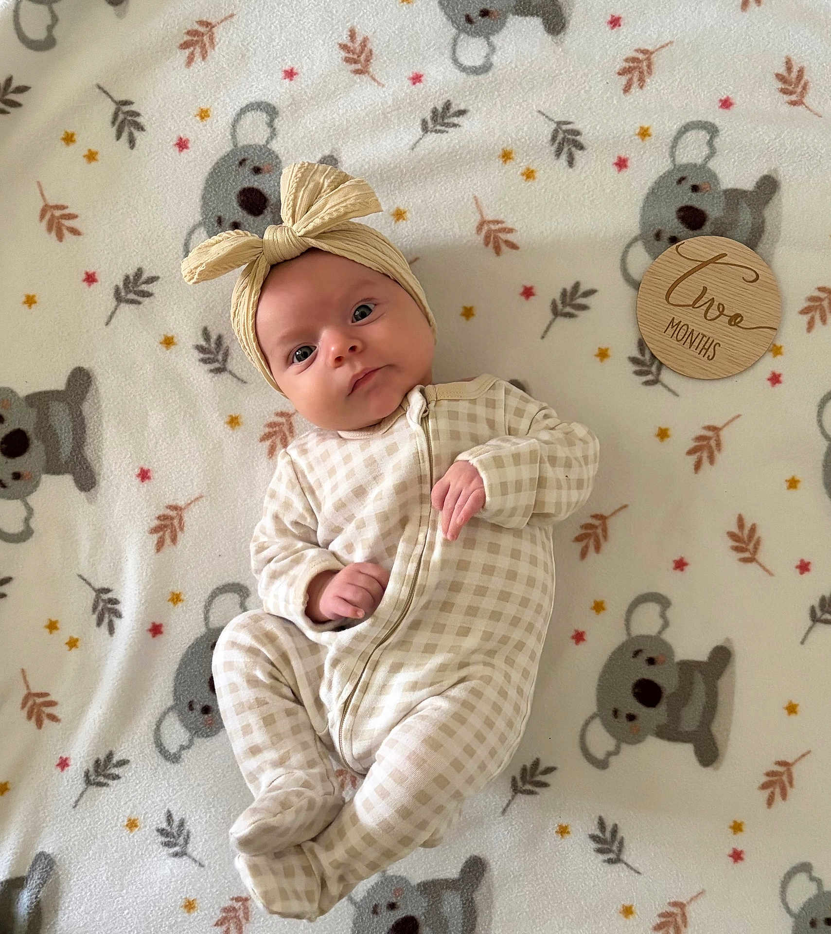 Alanis is registered to the contest to win money with this photo: baby, baby_boy, baby_clothes, blanket, child, cute, headband, indoors, infant, koala, lying_down, milestone, newborn, onesie, patterned_blanket, portrait, sleepwear, soft_texture, two_months, wooden_plaque