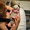 Bianca Rose is registered to the contest to win money with this photo: baby, infant, child, portrait, indoor, sitting, lying_down, flower_headband, romper, dress, smiling, face, hands, adult, caregiver, family, couch, pillow, handbag, coffee_table