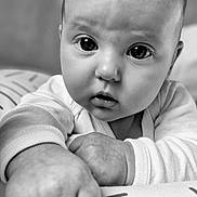 Khloé a rejoint le concours — aidez-le/la à gagner de superbes lots ! baby, infant, close_up, black_and_white, hand, face, eyes, curious, cushion, pattern, soft_lighting, chubby, portrait, child, young, cute, resting, expression, monochrome, indoors