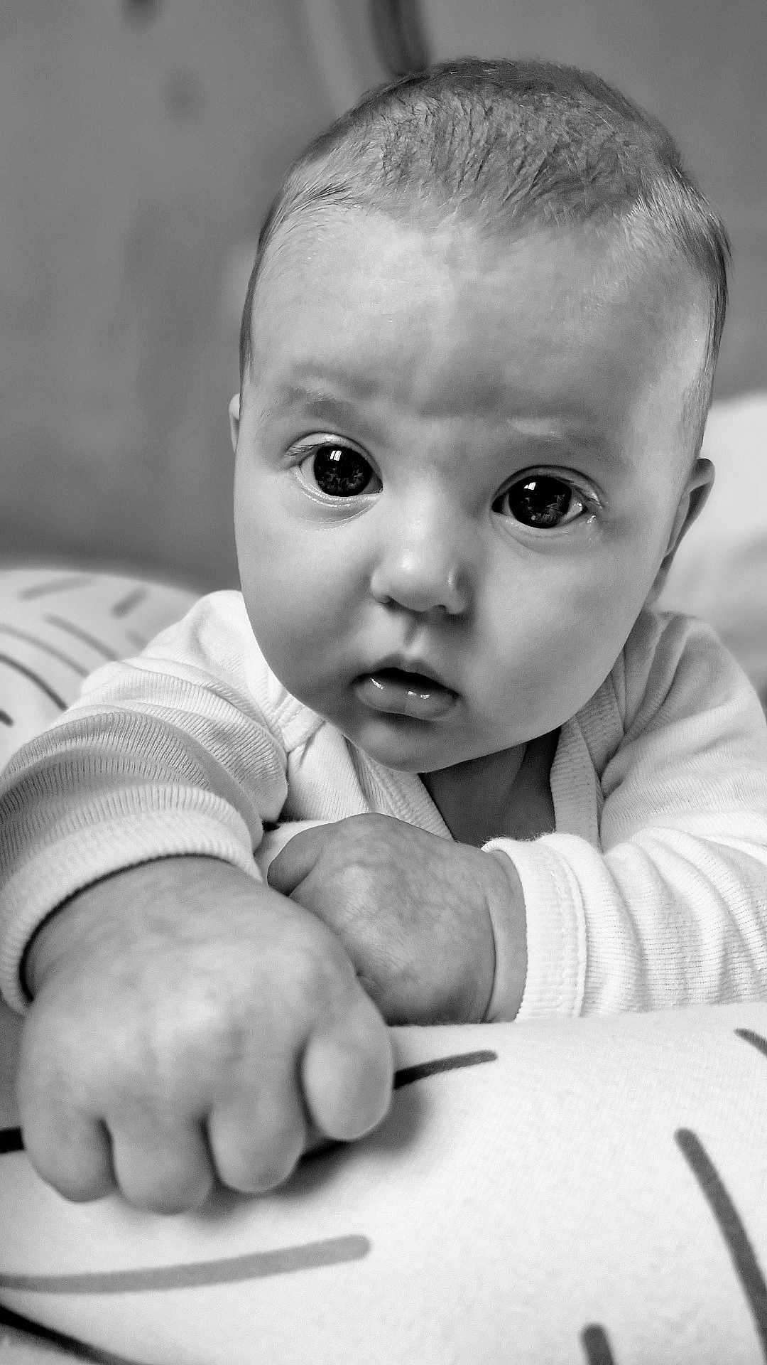 Khloé a rejoint le concours — aidez-le/la à gagner de superbes lots ! baby, infant, close_up, black_and_white, hand, face, eyes, curious, cushion, pattern, soft_lighting, chubby, portrait, child, young, cute, resting, expression, monochrome, indoors