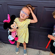 Kabriellalynn is registered to the contest to win money with this photo: child, girl, glasses, yellow_dress, plush_toy, minnie_mouse, smiling, standing, outdoor, concrete, garage_door, playful, happy, sneakers, hair_up, person, toy, casual, summer, friends