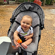 Elizabeth joined the competition — help win amazing prizes! baby, stroller, smile, blue_eyes, toy, outdoor, playground, child, happy, seat, foot, grass, tree, hand, person, clothing, nature, daylight, expression, park