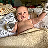 Bentley is registered to the contest to win money with this photo: baby, infant, smiling, mitten, blanket, pillow, face, child, happy, cozy, bedroom, soft, cute, person, portrait, lying_down, home, comfort, young, expression